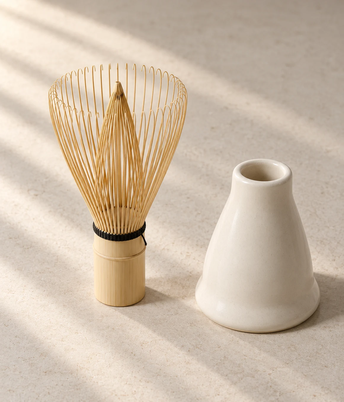 Split bamboo whisk tines and hollow ivory ceramic whisk holder in warm window light