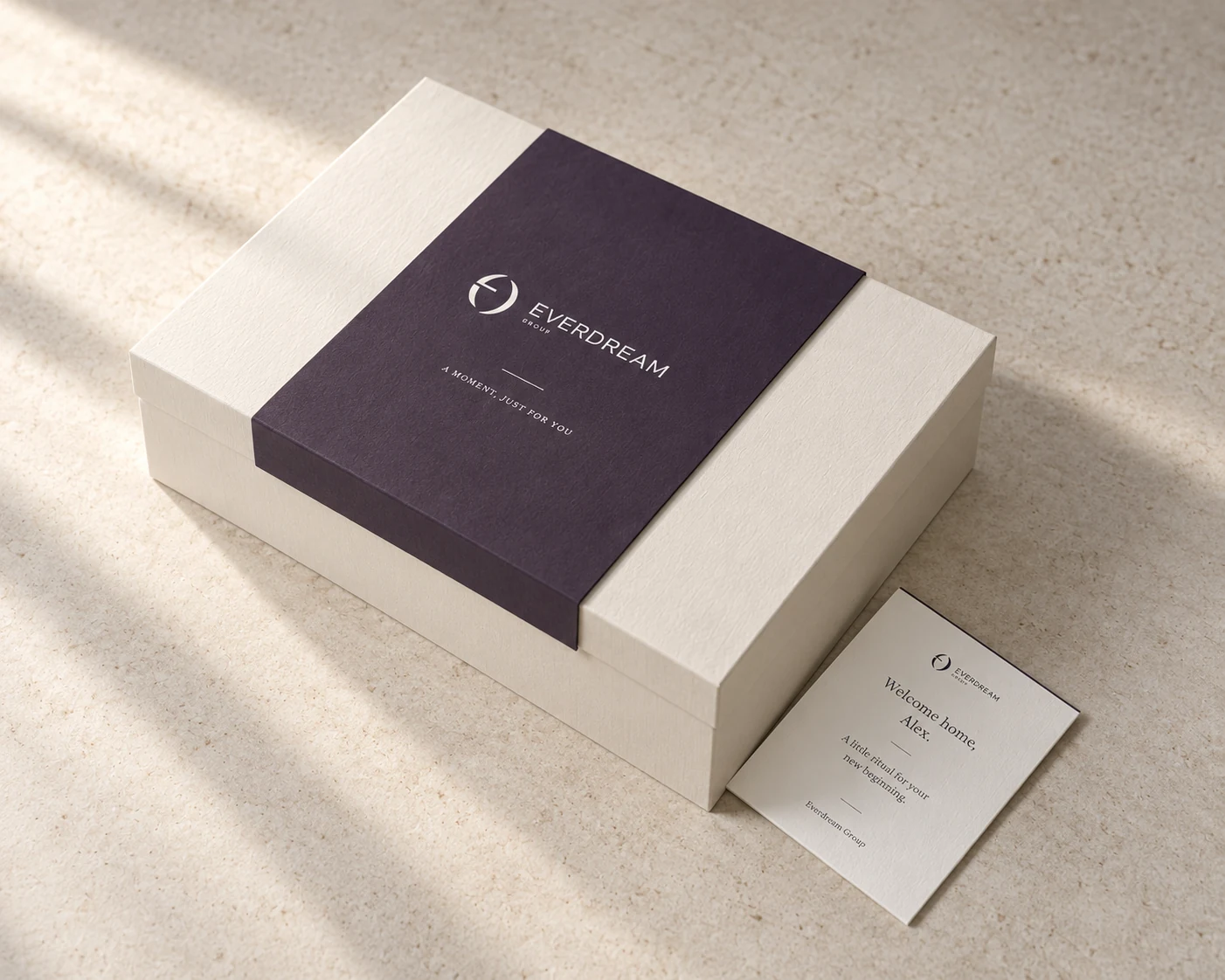 An ivory gift box with aubergine sleeve and personal card in warm window light